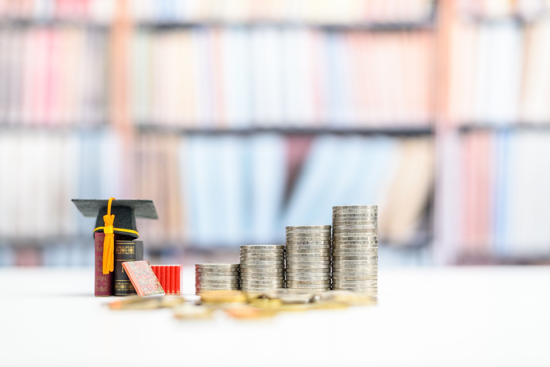 Student loan and financial decision-making, financial literacy concept : Graduation cap, books and coins on a table.